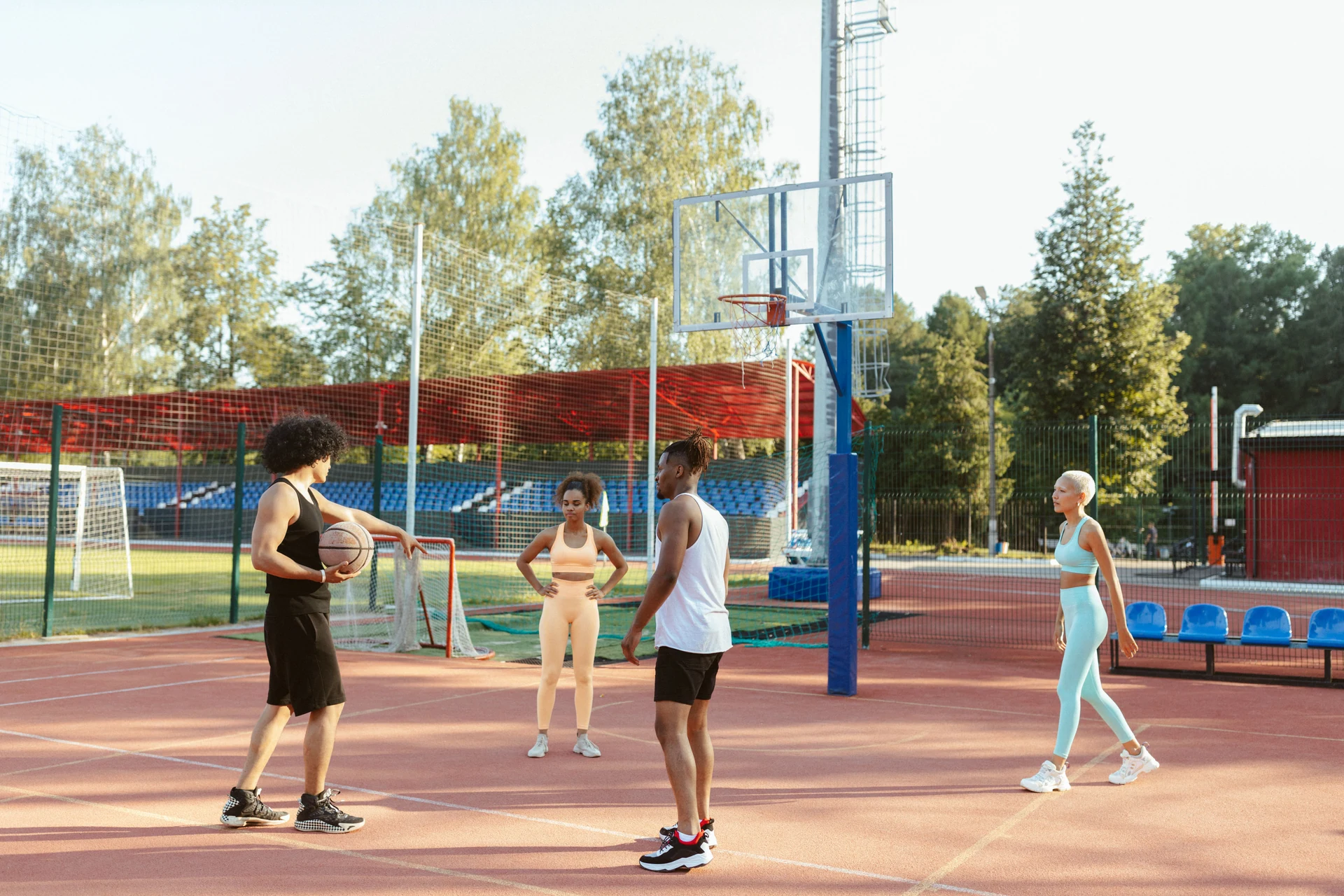 Women and men playing basketball together on an outdoor court